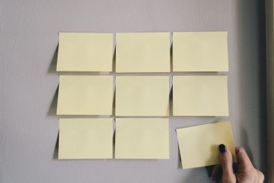 hand putting up nine blank yellow post-its