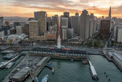 Photo of sunset overlooking the San Francisco skyline with buildings in the background and the Port San Francisco in the foreground.